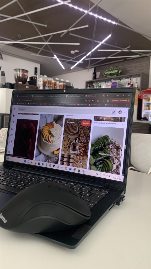 Laptop in a café showing a Pinterest moodboard of cakes, cookies and cozy aesthetics